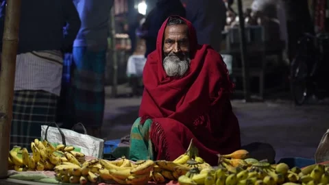 View of an elderly man in a red shawl selling bananas, Bangladesh. Video stock 335550837