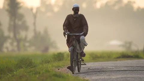 View of an elderly man riding a bicycle on a misty road, Bangladesh. Video stock 334968022