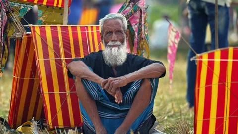 View of an elderly man sitting among colorful kites in Bangladesh. Video stock 335014361