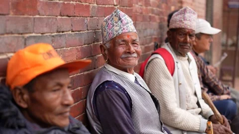 View of elderly Nepalese men sitting against a brick wall, Nepal. Video stock 335469765