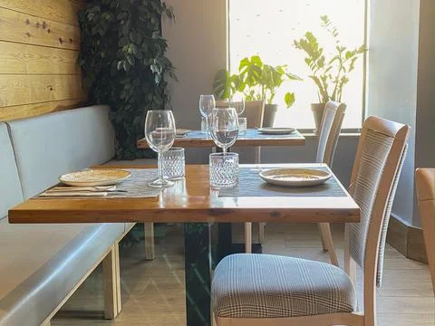 View of an elegant and cozy empty cafeteria with tables, chairs and cutlery l Stock Photos