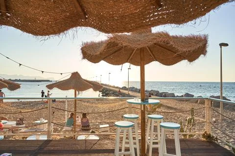 View on empty bar table against sunset at the beach. Summer time in Italy. Stock Photos