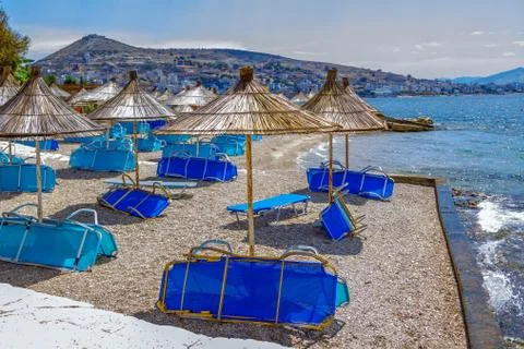 View of empty beach -  blue deck chairs and shade umbrellas near sea water Stock Photos