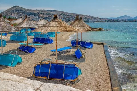View of empty beach - blue deck chairs and shade umbrellas Stock Photos