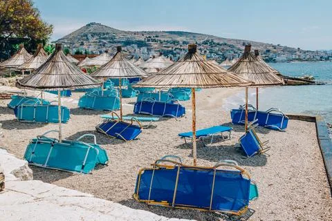View of empty beach - blue deck chairs and shade umbrellas Stock Photos