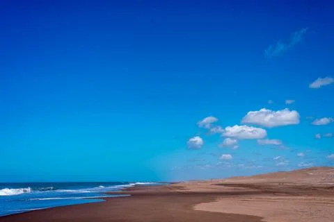 View of an empty beach with sand dunes on a sunny day. Summer and travel concept Stock Photos