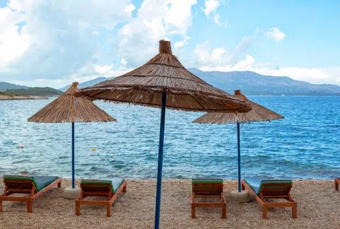 View of empty beach – sun bads and umbrellas near sea water Stock Photos