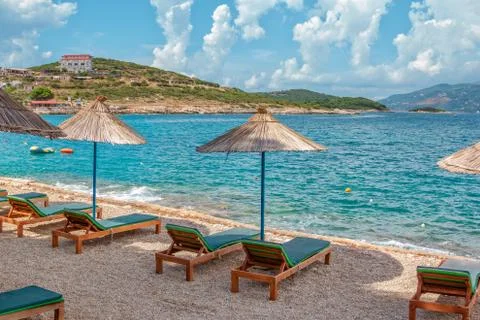View of empty beach - sun bads and umbrellas near sea water Stock Photos