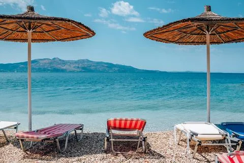 View of empty beach - sun beds and umbrella near sea water Stock Photos