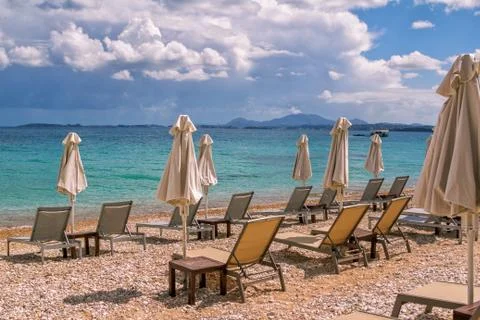 View of empty beach - white deck chairs and umbrellas near sea water Stock Photos