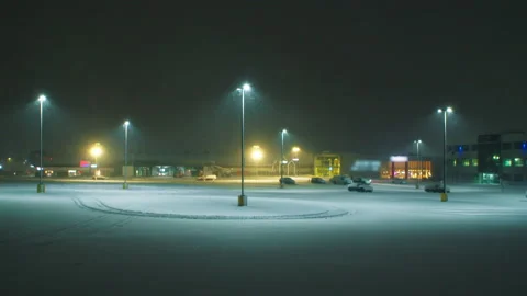 View of an empty car park with tall night lights and heavy storm snow. Stock Footage 234901705