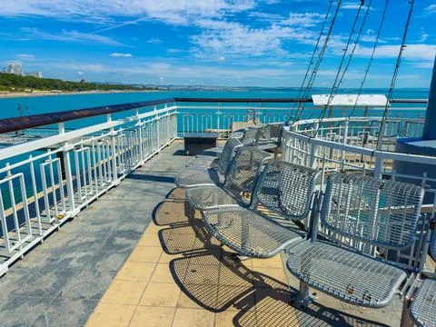View of empty metal chairs on a deck overlooking the water during a sunny d.. Stock Photos