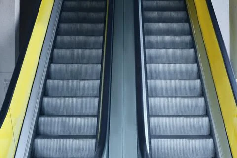 View on empty parallel escalators with yellow balustrades Stock Photos