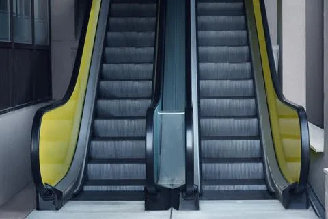 View on empty parallel escalators with yellow balustrades Stock Photos