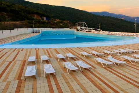 View of the empty pool, sun loungers and city water park in the morning at da Stock Photos