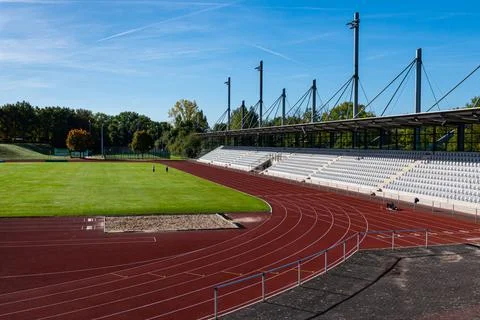 View of the empty stands of the stadium with a green field and a running trac Stock Photos