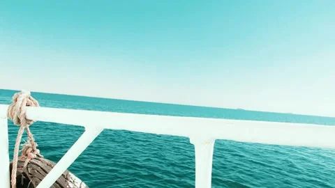 View of the endless blue sea from the side of a boat with white railings Stock Footage 312033450