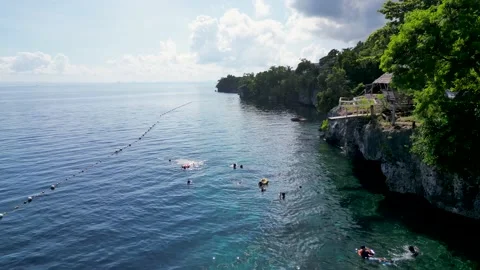 View of endless ocean and rocks with springboard on right. Tourists swim and Stock Footage 232645462
