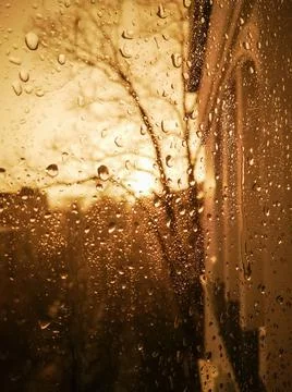 View of the evening city, shot from the inside through glass with rain drops. Stock Photos