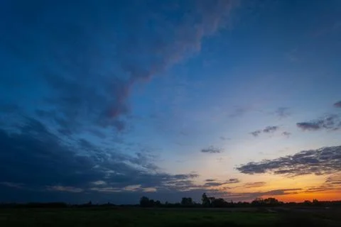 View of evening clouds and sky after sunset over a meadow Stock Photos