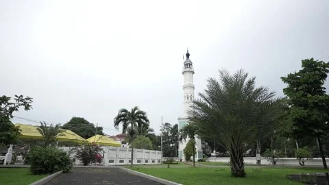 View of the expansive courtyard of a mosque with palm trees and mosque minarets Stock Footage 258886100