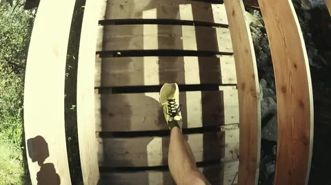 View from eye level with a man  wearing sneakers passing the wood bridge Stock Footage 53914749