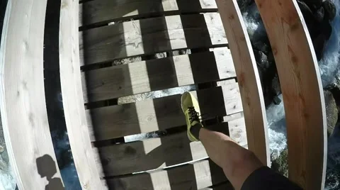 View from eye level with a man  wearing sneakers passing the wood bridge Stock Footage 53914991