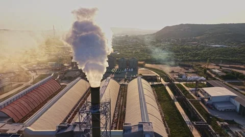 View of factory with smoke stack and large storage buildings at sunset 動画素材 340384027