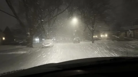 View of fast falling snowflakes illuminated by vehicle headlights while driving Stock Footage 340562921