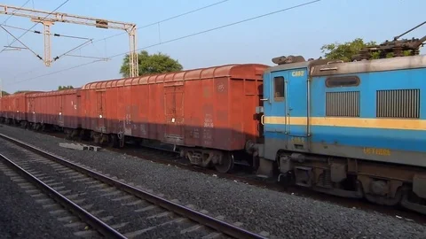 View from fast moving train,crossing stationery old Freight train, Gujarat India Stock Footage 106799271