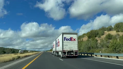 View of Fed Ex semi truck with double trailers driving on freeway. FedEx Vidéo 227970751