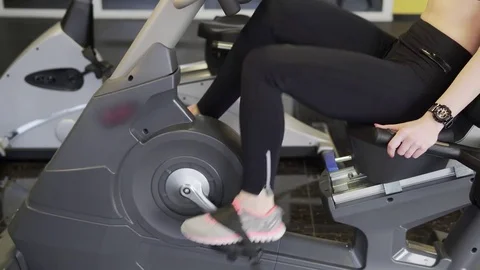 A view of the feet of a woman who quickly turns the pedals on a sports bicycle. Stock Footage