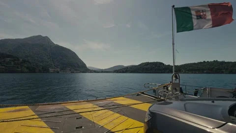 View from Ferry Loading Ramp with Italian Flag Crossing Calm Alpine Lake Stock Footage 340901114