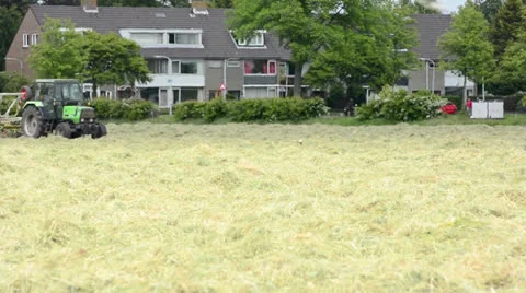 View of the field and green harvesting machine close to the village Stock Footage 24919081
