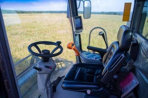 View of the field of corn from the cab of a combine harvester on a sunny day. Stock Photos