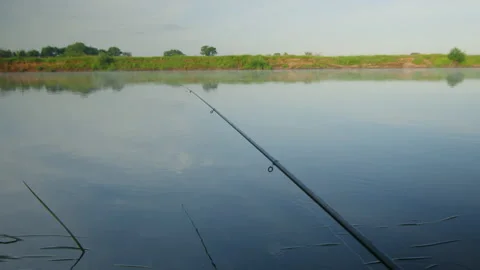 View of a fishing rod while fishing on the lake in the early morning Stock Footage 237361853