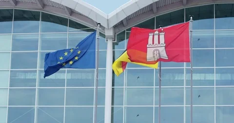 View of flags flying in light breeze in front of Hamburg Messe Stock Footage 77077318