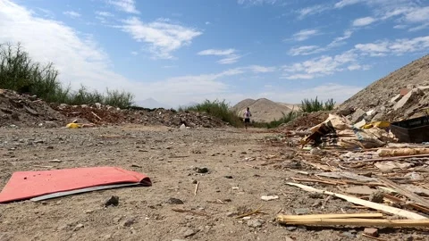 View from the floor of a running man approaching through garbage in the farmland Vidéo 197087665