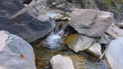 View to a flowing rapidly raced down narrow stream pond of water between boulder Stock Footage 265491615