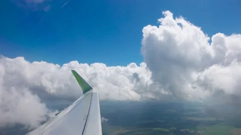 The view from the flying airplane window on clouds and wing of plain under blue Stock Footage 235291366