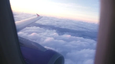 View from flying airplane window wing and white clouds while morning sunrise Stock Footage 104789604