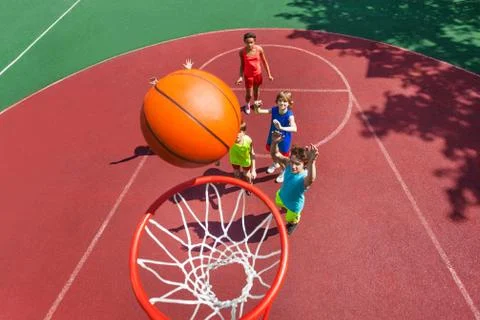 View of flying ball to basket from top, teens play Stock Photos