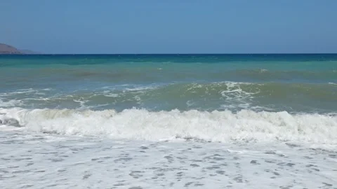 View of foaming sea waves breaking on pebble beach against clear sky background. Stock Footage 346525513
