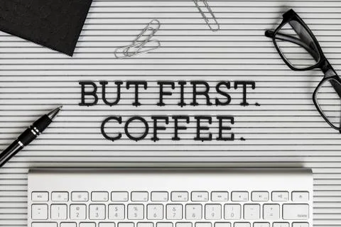 View form above "But First Coffee" on desk above computer keyboard Stock Photos
