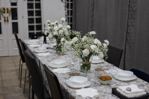 View of a formal dinner table with white tableware and flowers Stock Photos