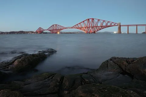 View of Forth Rail Bridge in the evening and the rocky coast in the foreground Stock Photos