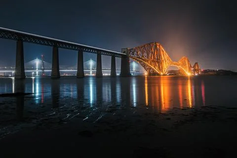 View of Forth Rail Bridge at night and and the glow trail of a moving train over Stock Photos
