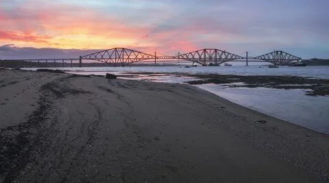 View of Forth Rail Bridge at sunset and the sandy coast in the foreground Stock Photos