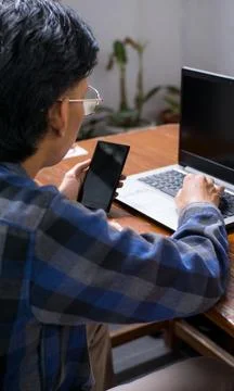 View of a Freelancer Multitasking with Smartphone and Laptop Stock Photos