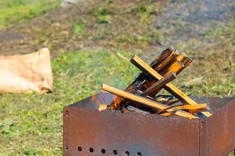 View of fresh firewood, thin chips in the fire, which burn in a metal grill Stock Photos